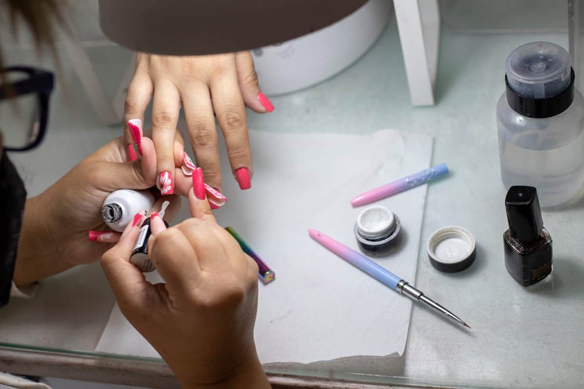 Maniküristin appliziert rote Acrylnägel